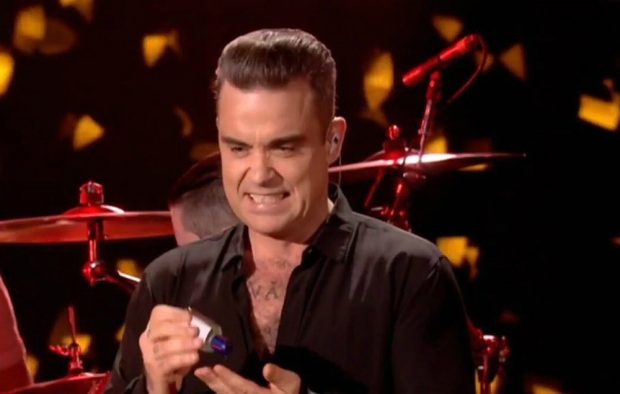 Robbie Williams uses hand sanitiser after shaking hands with fans