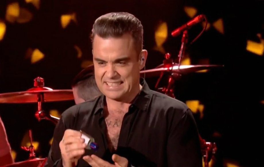 Robbie Williams uses hand sanitiser after shaking hands with fans