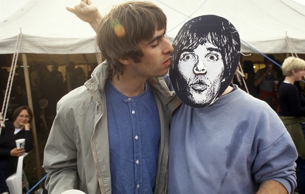 Liam Gallagher backstage with a fan in an Ian Brown mask at Glastonbury 1995