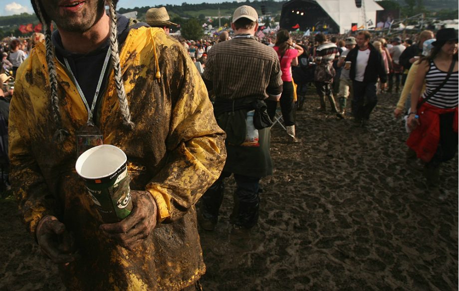 A muddy man with booze at a festival